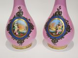 une paire de vases roses ornés d'une bordure dorée et représentant une femme dans un jardin