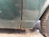 a dirty green car that is parked on the side of the road