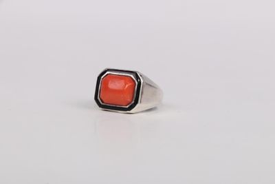 a close up of a ring with a red stone in it