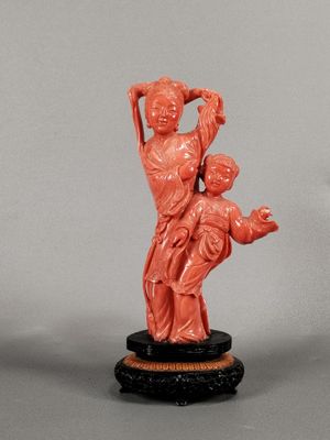 une statue orange représentant une femme tenant un enfant dans ses bras, posée sur un socle noir