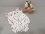 a baby girl ' s outfit next to a pair of baby shoes