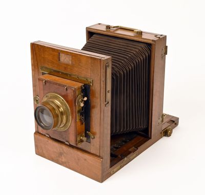 un vieil appareil photo en bois posé sur une surface blanche, avec un fond blanc