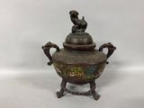 an antique bronze teapot with a bird on top