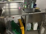 a sink in the corner of a kitchen with a lot of cleaning supplies
