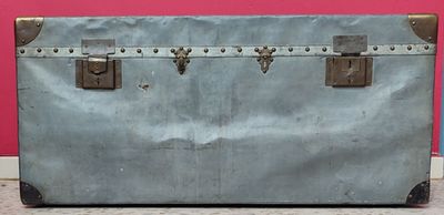 une vieille valise posée par terre devant un mur rose