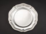 une assiette en argent posée sur une table noire, sur fond noir