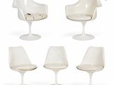 four white tulip chairs and a chair with a cushion