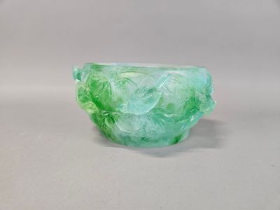 translucent green glass bowl on a white surface with a white background