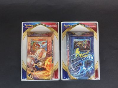 Deux boîtes de cartes Pokémon sont posées côte à côte sur une table.