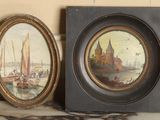 two framed pictures of boats on a table