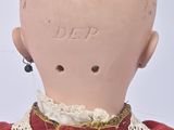 a small doll with a red dress and a white lace collar