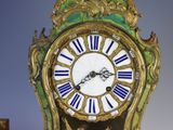 a gold clock with blue and white roman numerals on it