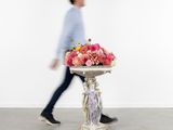 un homme passant devant un vase orné de fleurs