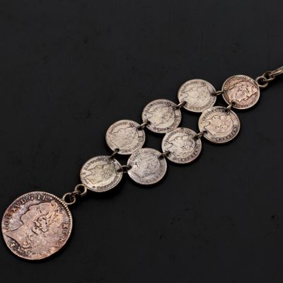 un gros plan d'un bracelet composé de pièces de monnaie posé sur une surface noire