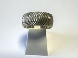 un gros plan d'une bague en argent posée sur un support, sur une surface blanche