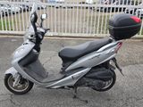 un scooter garé sur un parking, avec un casque posé dessus