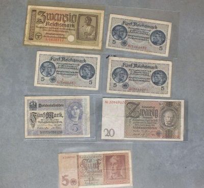 Plusieurs anciens billets de banque allemands sont exposés dans une vitrine.