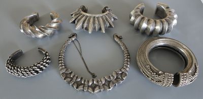 des bijoux en argent posés sur une table, avec un bracelet en argent et d’autres objets
