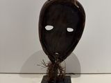 an image of a wooden sculpture of a face with a plant growing out of it ' s mouth