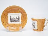 a cup and saucer sitting next to a picture on a plate