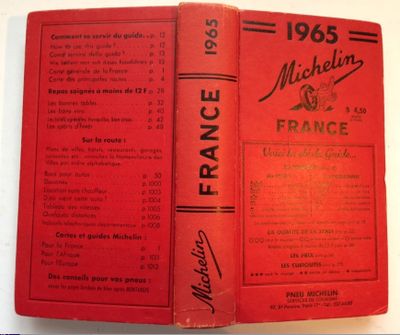 an old book with a red cover sitting on top of a table