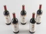 six bottles of wine are lined up in a row on a white surface