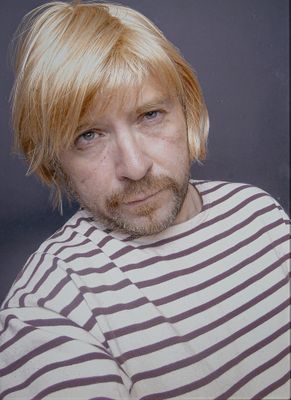 a man with blonde hair wearing a striped shirt