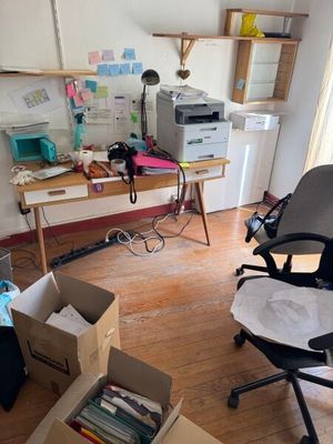 une pièce équipée d'un bureau, d'une chaise, d'une imprimante et d'autres objets