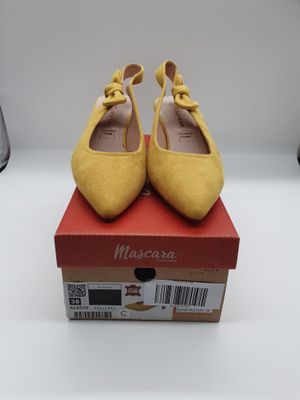 des chaussures jaunes ornées de nœuds, posées sur une boîte