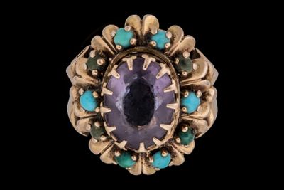 un gros plan d'une bague ornée d'une pierre violette entourée de pierres turquoise