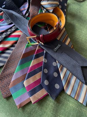 many ties laid out on a green table cloth