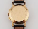 a close up of a gold watch with a brown leather strap