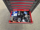 une boîte à outils rouge contenant des outils, posée dans la rue