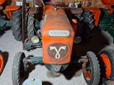 a small tractor in a garage with other farm equipment