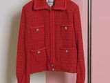 La veste rouge est suspendue à un cintre devant un mur rose.
