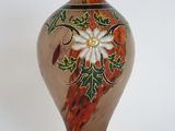 a glass vase with a flower on it on a white surface