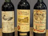 three bottles of wine are lined up on a wooden table