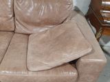 a brown leather couch with pillows on it in a room