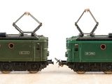 two green trains sitting side by side on a wooden table