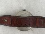 an image of a watch with a brown leather band on a white surface