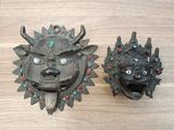 une paire de masques en métal posés sur une table en bois, ornés de perles rouges et bleues
