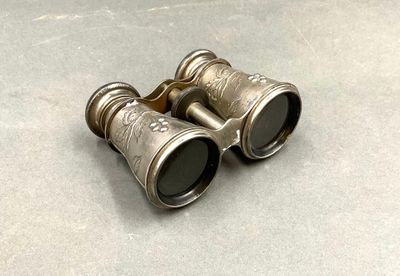 une paire de jumelles anciennes en argent posée sur une table