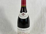 une bouteille de vin posée sur une table, à côté d'une nappe blanche