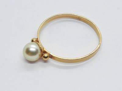 Gros plan sur une bague en or ornée d'une perle