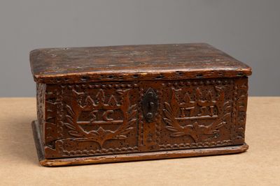 une vieille boîte en bois ornée de sculptures, posée sur une table