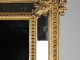 a mirror with a gold frame and a bird on it