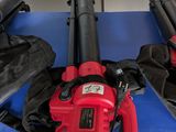 un ventilateur rouge posé sur une table bleue, à côté de deux ventilateurs noirs