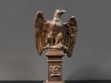 statue d'un aigle posée sur un socle, sur une surface noire