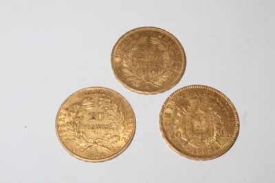 three gold coins sitting on top of each other on a white surface