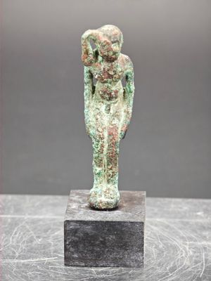 un gros plan sur la statue d'une personne posée sur un bloc de marbre